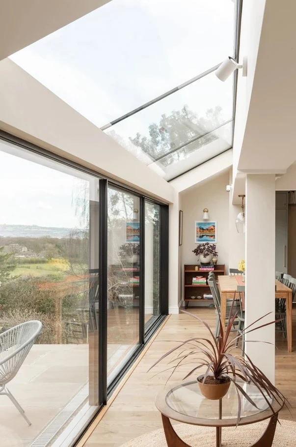Dining area at Hilltop House overlooking the landscaped garden through wide sliding glazing